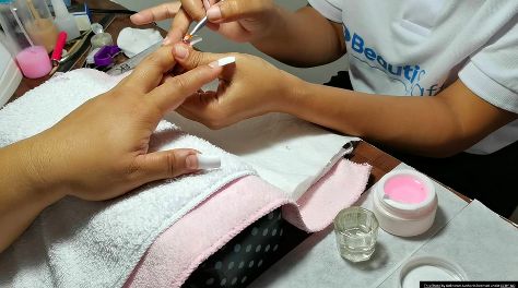 En person som får en professionell nagelbehandling under en nagelutbildning.