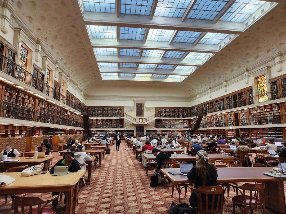 Studenter repeterar inför tentor i en stor universitetsbibliotekssal