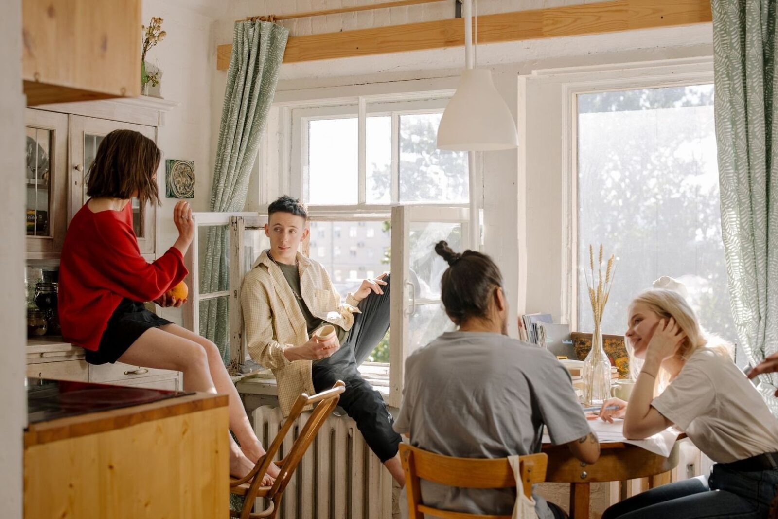 Flera unga samlas och samtalar i ett ljust gemensamt kök